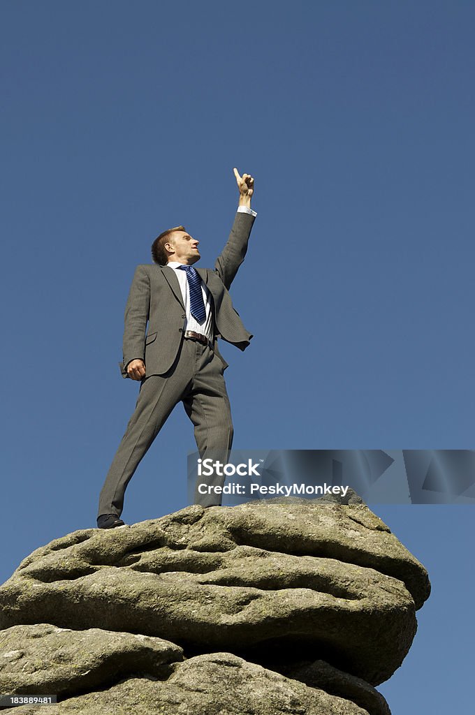 Geschäftsmann steht auf dem Berggipfel zeigt auf den Himmel - Lizenzfrei Anreiz Stock-Foto