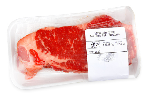 A packaged steak sits isolate on a white background.