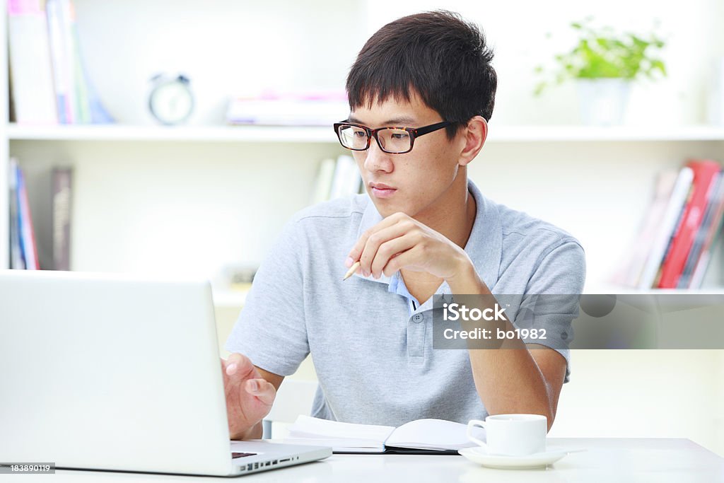 Giovane uomo che lavora con il computer portatile in ufficio a casa - Foto stock royalty-free di Adulto