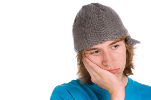 Sad teen wearing skater hat with his head in hand
