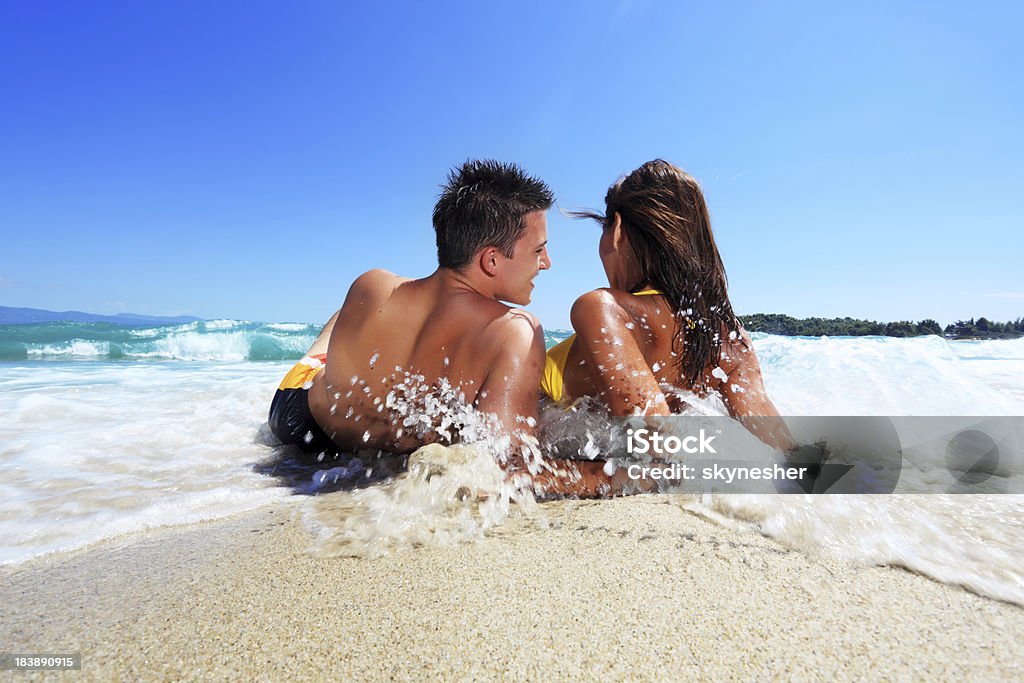 Young couple lying on the beach. Rear view of a couple lying on the beach and talking. Beach Stock Photo