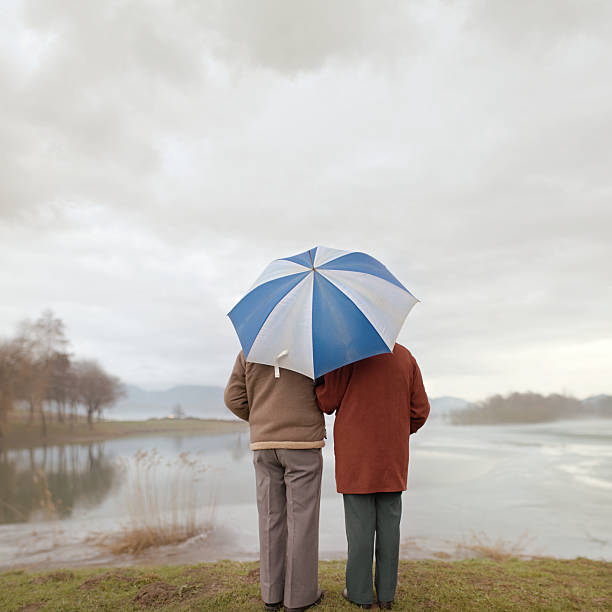 les jours de pluie - umbrella senior adult couple autumn photos et images de collection