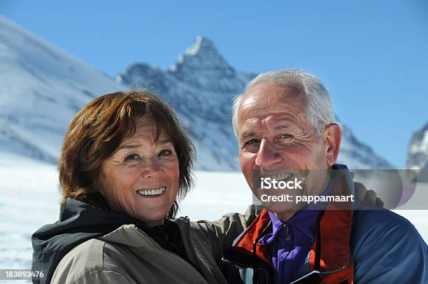 Romantische Glückliches Senior Paar Blick In Die Kamera Mit Snowy Mountains Stockfoto und mehr Bilder von 60-69 Jahre