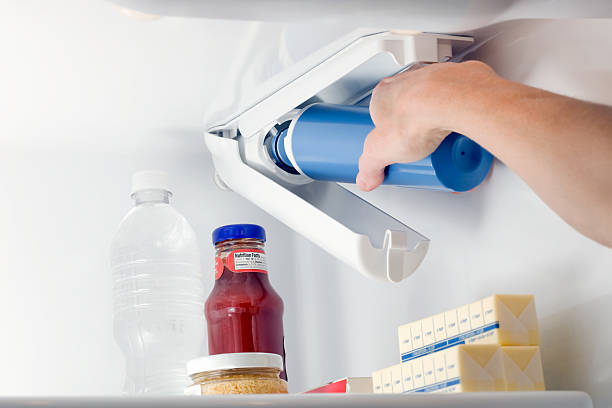 weibliche hand kühlschrank water filter ändern - beleuchtungstechnik stock-fotos und bilder