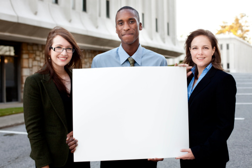 Cheerful business people holding a blank sign