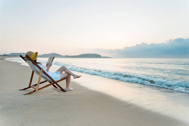 istock Woman reading book at the beach 1838958170