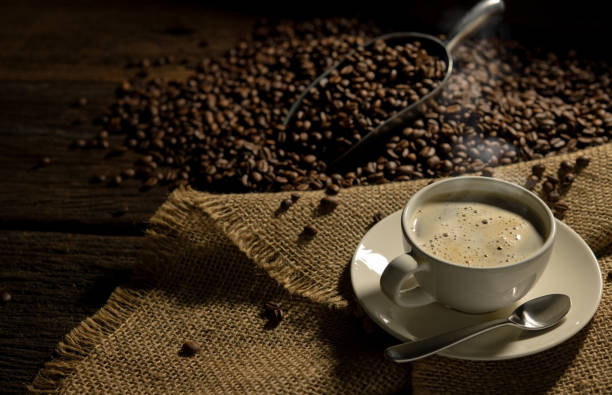 istock Coffee cup and coffee beans on burlap sack on old wooden table 1838978253