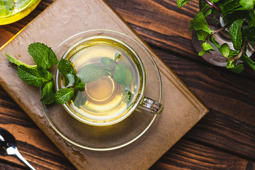 Mint tea in a teapot and cup on a wooden table