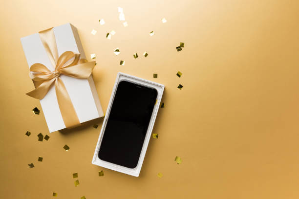 istock Opened gift box with gold ribbon and smartphone on color background, top view. Blank open box packaging mockup , Template for your design - branding mockup 1838986091