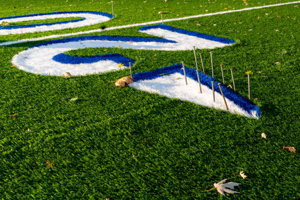 Synthetic turf field under construction with lines and graphics being installed.