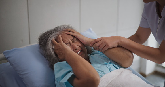 Portrait of Elderly female patient who was hospitalized was holding her head on the hospital bed in pain,severe headache