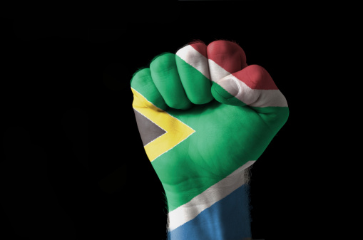 Low key picture of a fist painted in colors of south africa flag