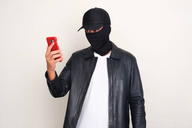 An online scammer looking to mobile phone that he hold with threatening gesture