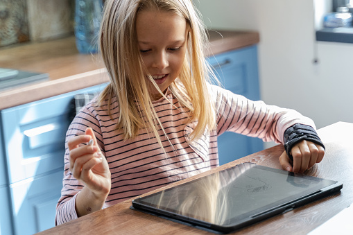 Girl studying at home with digital tablet in post pandemic times.