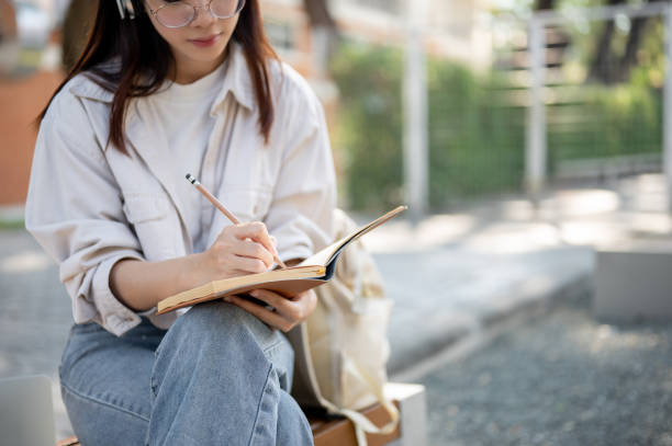 istock A female is keeping her diary or taking notes in her notebook while resting on a bench in a park. 1839182292