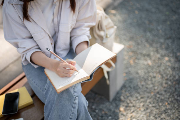 istock A female is keeping her diary or taking notes in her notebook while resting on a bench in a park. 1839183317