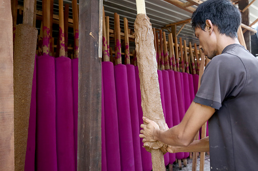 A Myanmar ethnicity man is sculpting oversized Joss Stick in Factory - Daily Production Activities