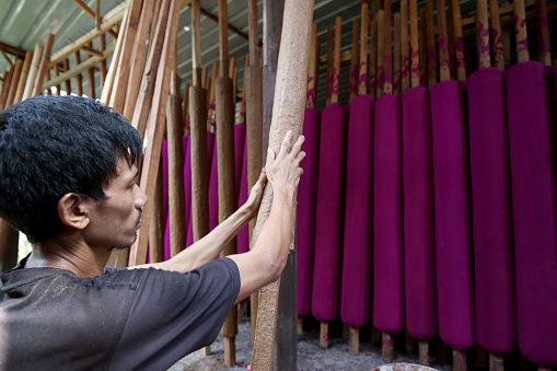 A Myanmar ethnicity man is sculpting oversized Joss Stick in Factory - Daily Production Activities