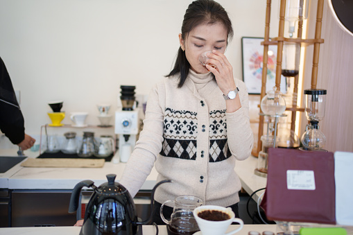 Asian woman tasting coffee