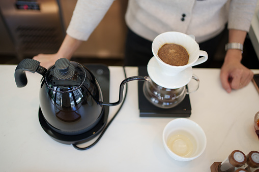 Grinding coffee beans in a manual coffee grinder on a wooden table. Copy space