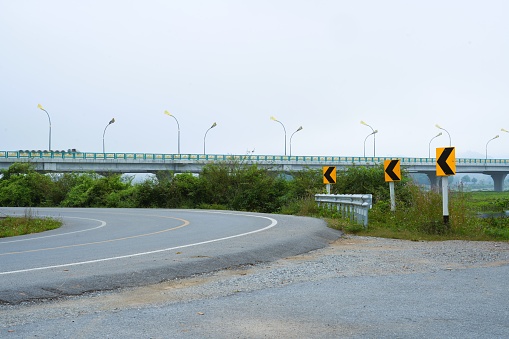 Signs indicate curves and the road curves before a large bridge.