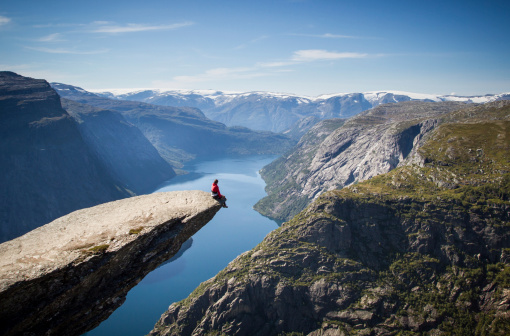 Hombre sentado en trolltunga en Noruega photo