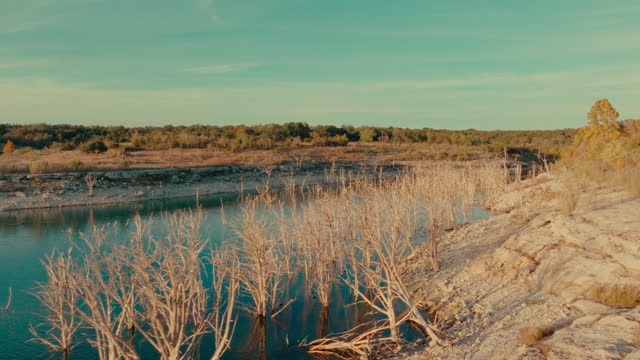 Drone flight along serene Lake Georgetown, Texas shoreline at sunset in fall