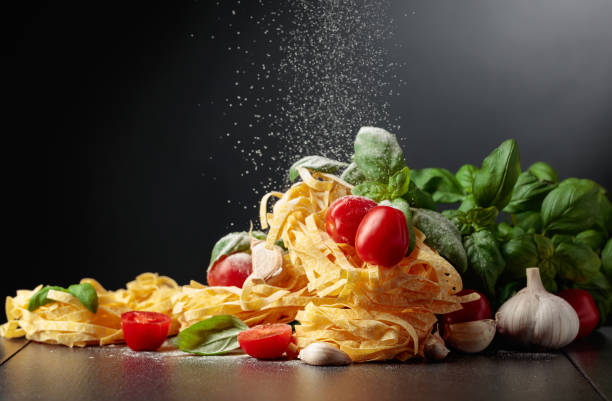 istock Homemade raw pasta with tomato, garlic, and basil on a black background. 1839427253