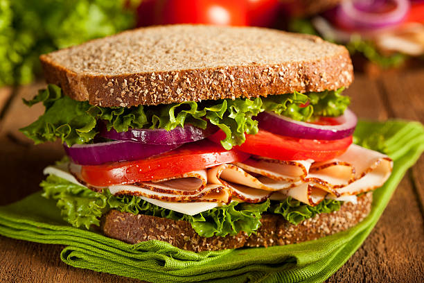 A sandwich with tomatoes, onions, and lettuce on wheat bread Homemade Turkey Sandwich with Lettuce, Tomato, and Onion sandwich stock pictures, royalty-free photos & images