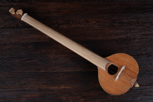 Turkish tambour. Long-necked folk string instrument of the lute family on wooden table.