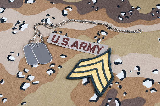 US ARMY sergeant rank patch and dog tags on Desert Battle Dress Uniform background