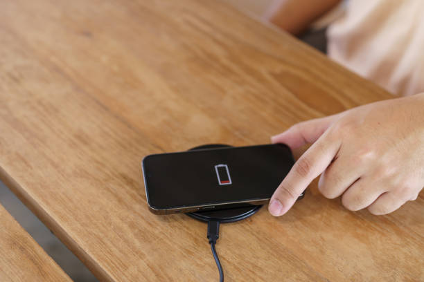 istock Charging mobile phone battery with wireless charging device in the table. Smartphone charging on a charging pad. Mobile phone near wireless charger Modern lifestyle technology concept. 1839465493