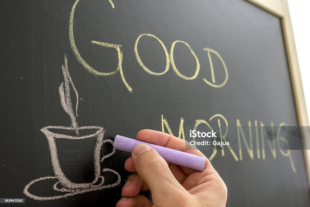 Good morning coffee cup Closeup of cafe owner writing good morning sign on black board. Aspirations Stock Photo