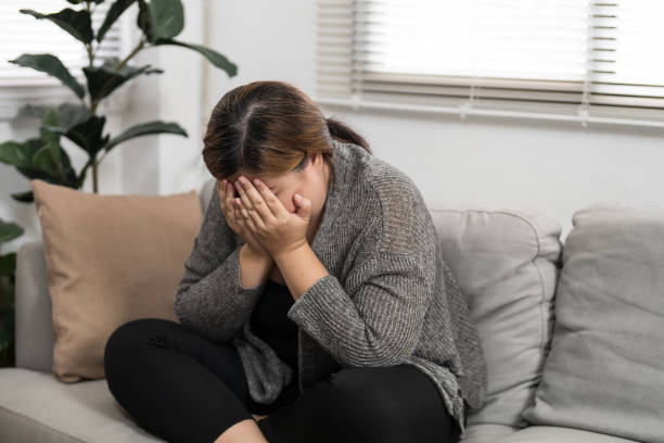 istock Sad Overweight plus size woman thinking about problems on sofa upset girl feeling lonely and sad from bad relationship or Depressed woman disorder mental health. 1839473885
