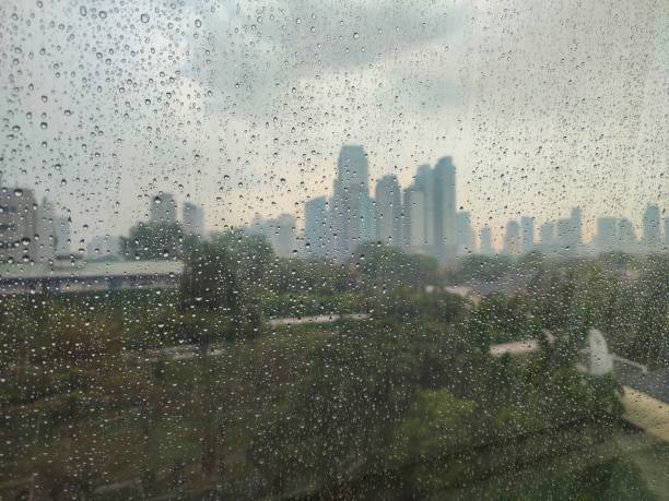 istock Raindrops on the window with garden and building background 1839499363