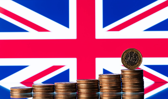 One pound coin against the background of a fragment of the flag of Great Britain