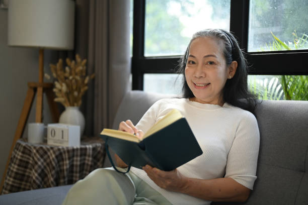 istock Happy senior woman relaxing on couch and reading book 1839522228