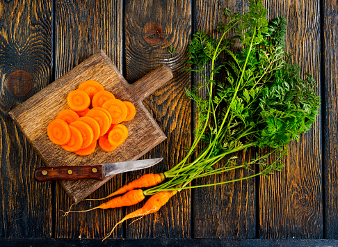 Wooden board with fresh carrots on wooden