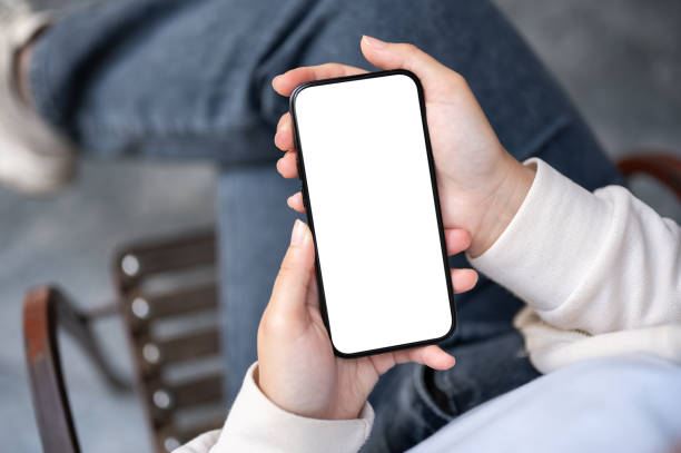 istock A woman in jeans using her smartphone while sitting outdoors. A white-screen smartphone mockup 1839534461