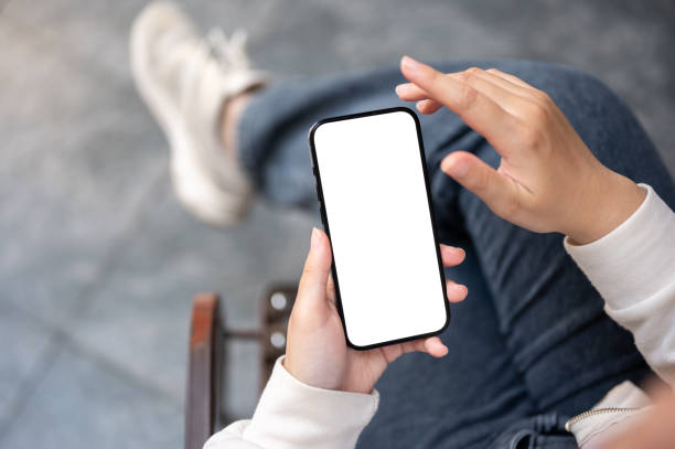 istock A woman in jeans using her smartphone while sitting outdoors. A white-screen smartphone mockup 1839534462