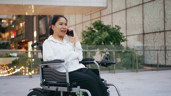 Hybrid Interaction: Businesswoman in Wheelchair Navigates Conversations Across Workforce with mobile phone