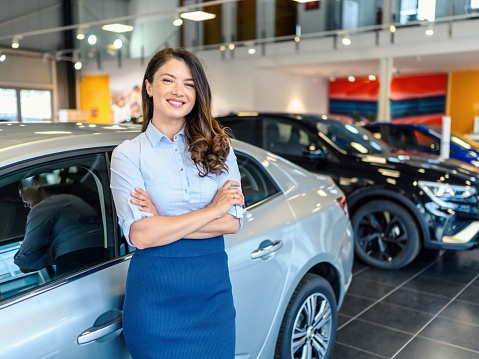 Portrait of a handsome female car saleswoman working in the showroom
