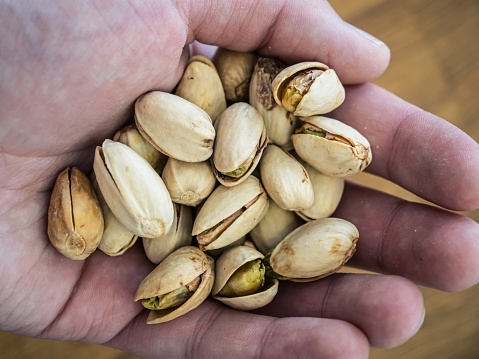 Closeup view of hand holding pistachio in shell nuts. Healthy food and snack. Pistachios great for healthy and dietary nutrition. Concept of nuts