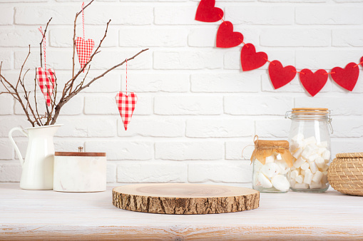 Podium on wooden table and kitchen containers over white brick wall decorated with red hearts