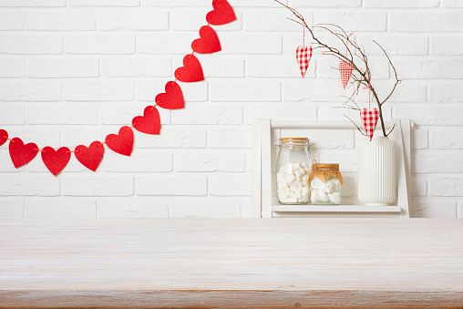 Wooden table top over white brick wall in kitchen decorated for Valentines day celebration