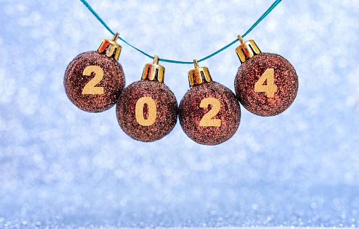 Shiny Christmas balls adorned with the inscription 2024 set against a sparkling festive background.