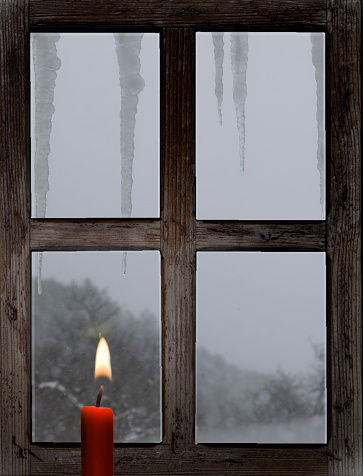 Old wooden window with Christmas candle and icicle