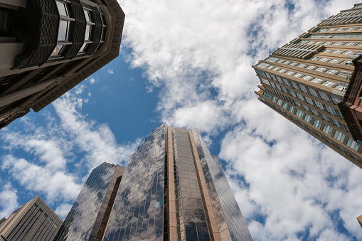 Low angle view of tall office buildings with blue sky and some clouds.