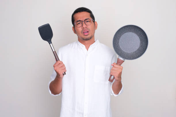 istock A man showing frying pan and spatula with confuse expression 1839646521