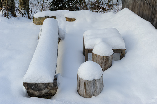 A Snow Covered Bench and Table in the woods